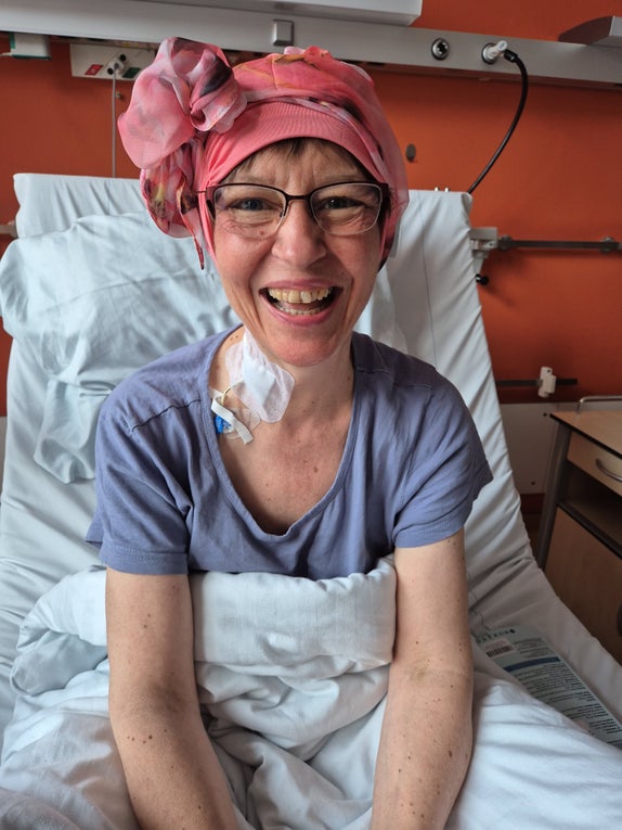 Anke sitzt im Krankenhausbett und lächelt in die Kamera  Anke sitzt im Krankenhausbett und lächelt in die Kamera