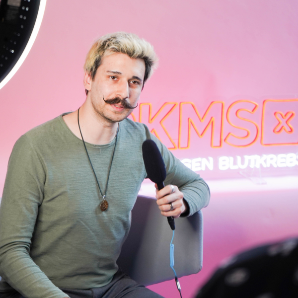 Ein Mann mit Schnurrbart hält ein Mikrofon Ein Mann mit Schnurrbart hält ein Mikrofon