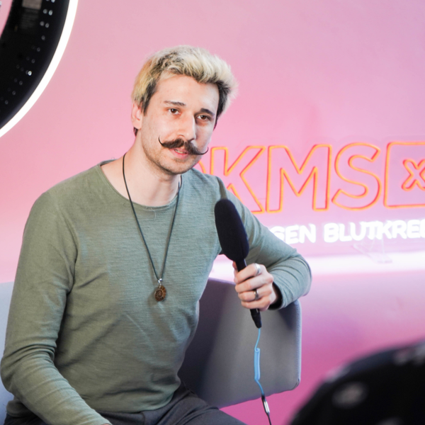 Ein Mann mit Schnurrbart hält ein Mikrofon Ein Mann mit Schnurrbart hält ein Mikrofon