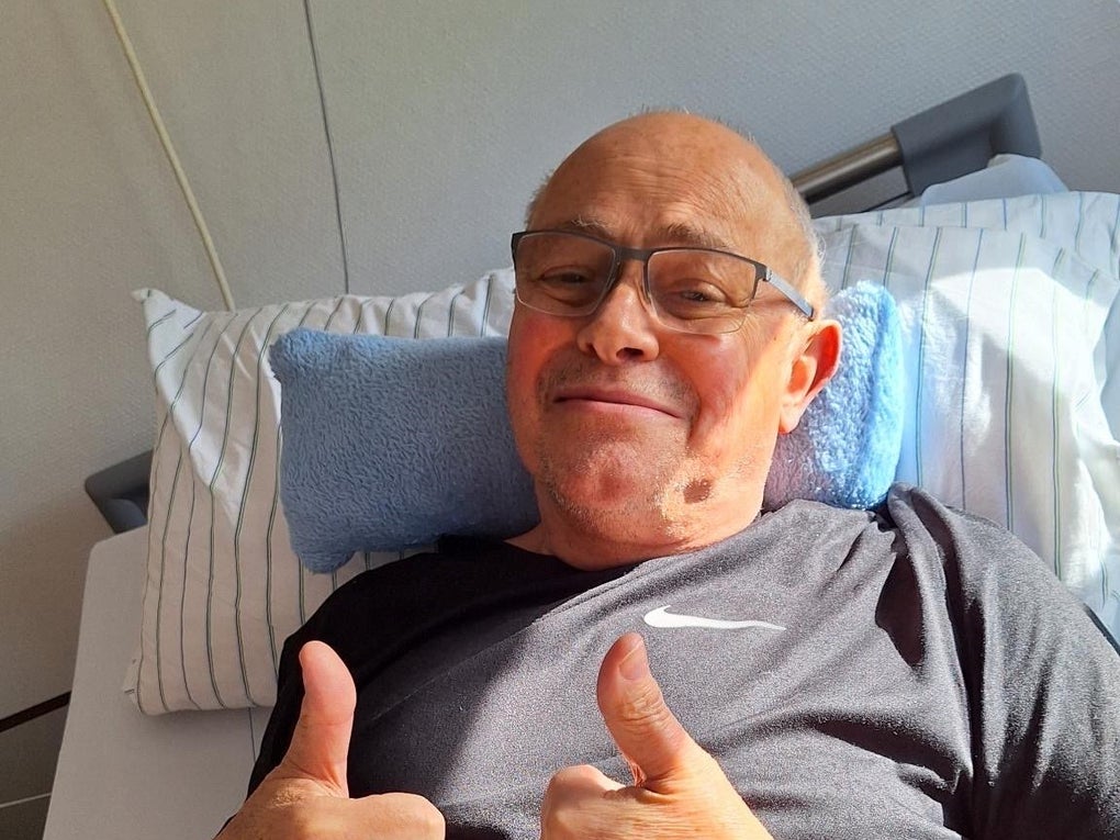 Ein Mann liegt in einem Krankenhausbett und zeigt mit beiden Daumen nach oben Ein Mann liegt in einem Krankenhausbett und zeigt mit beiden Daumen nach oben