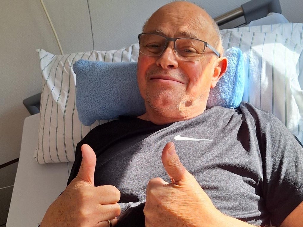 Ein Mann liegt in einem Krankenhausbett und zeigt mit beiden Daumen nach oben Ein Mann liegt in einem Krankenhausbett und zeigt mit beiden Daumen nach oben