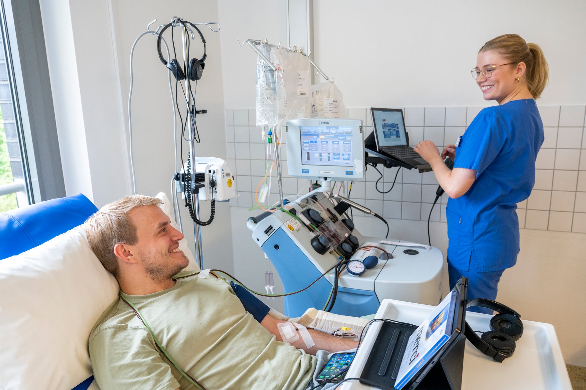 Ein Mann liegt in einem Bett, während einer Stammzellspende, daneben steht eine Pflegekraft Ein Mann liegt in einem Bett, während einer Stammzellspende, daneben steht eine Pflegekraft