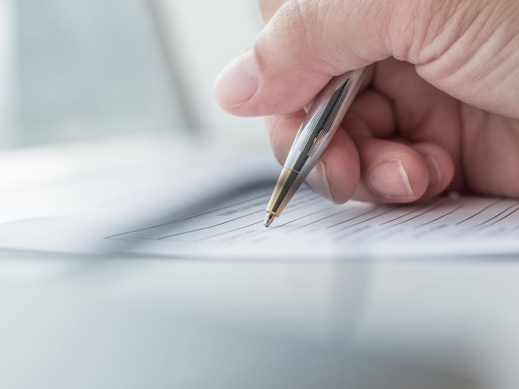Eine Hand, die einen Stift über ein Blatt Papier hält Eine Hand, die einen Stift über ein Blatt Papier hält