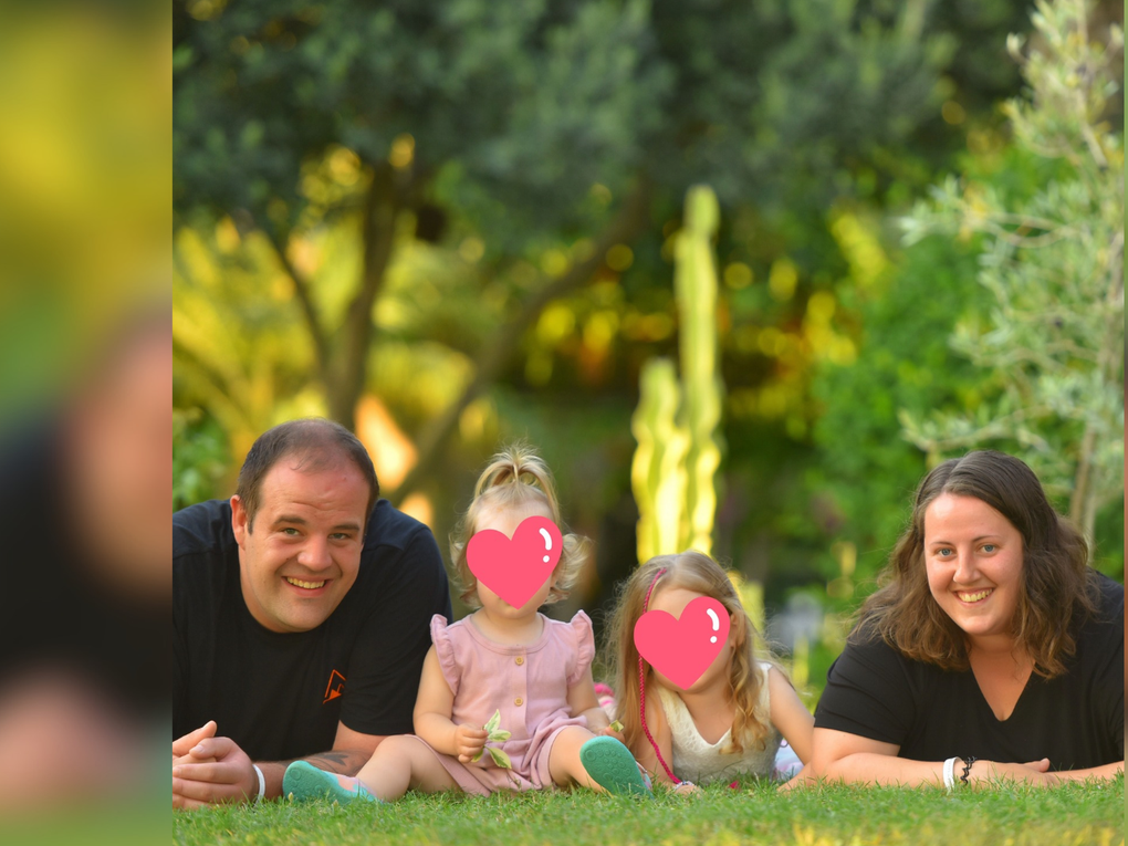 Ein Mann und eine Frau mit zwei Kindern, die auf dem Rasen liegen Ein Mann und eine Frau mit zwei Kindern, die auf dem Rasen liegen
