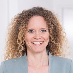 Eine Frau mit lockigem Haar lächelt, Jennifer Andersen Eine Frau mit lockigem Haar lächelt, Jennifer Andersen