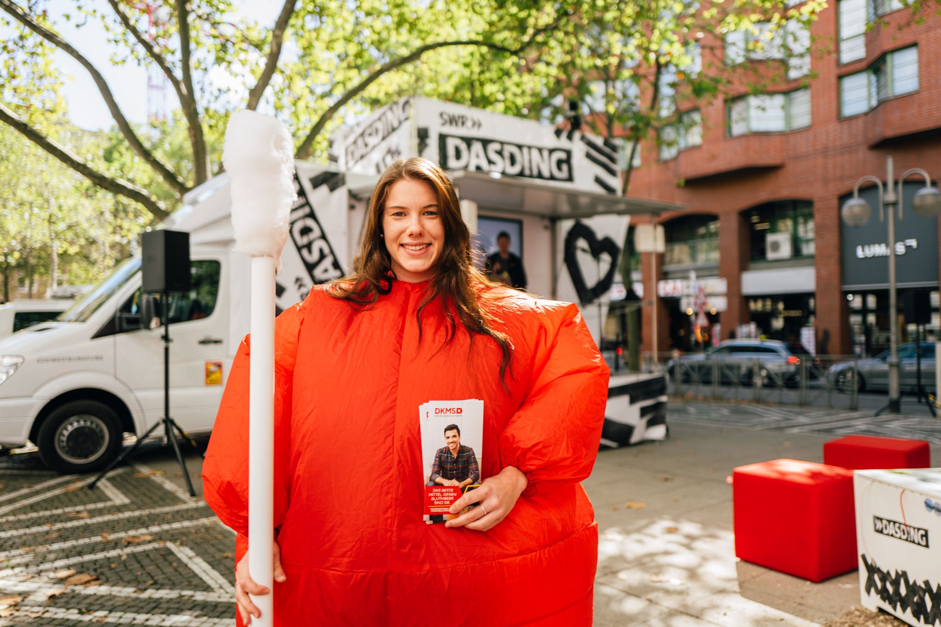 Eine Frau in einem orangefarbenen, geschwollenen Anzug hält ein Wattestäbchen Eine Frau in einem orangefarbenen, geschwollenen Anzug hält ein Wattestäbchen