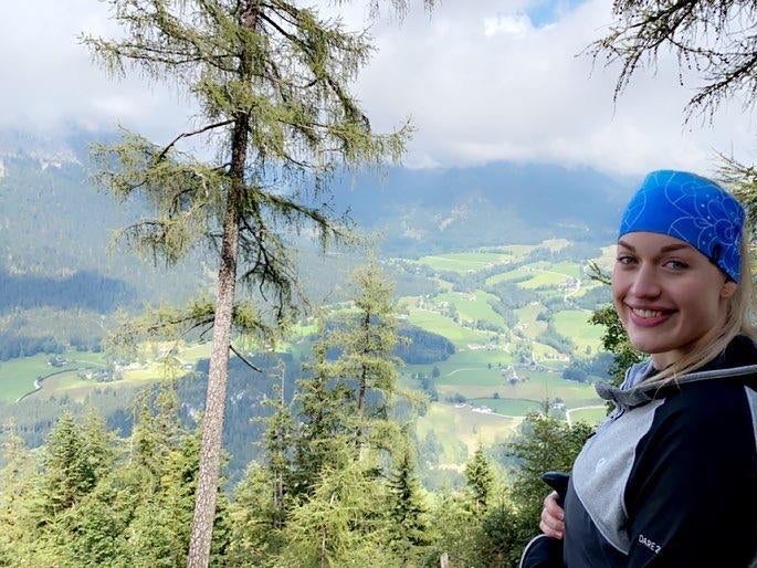 eine Frau steht auf einem Hügel, im Hintergrund sind Bäume und Felder zu sehen eine Frau steht auf einem Hügel, im Hintergrund sind Bäume und Felder zu sehen