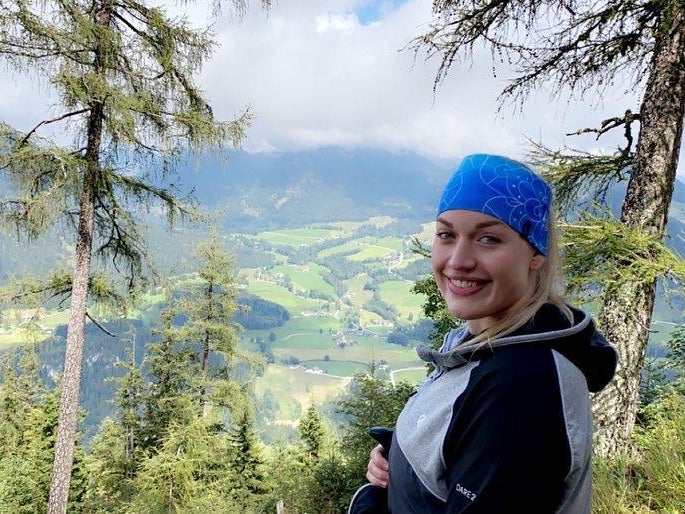 eine Frau steht auf einem Hügel, im Hintergrund sind Bäume und Felder zu sehen eine Frau steht auf einem Hügel, im Hintergrund sind Bäume und Felder zu sehen