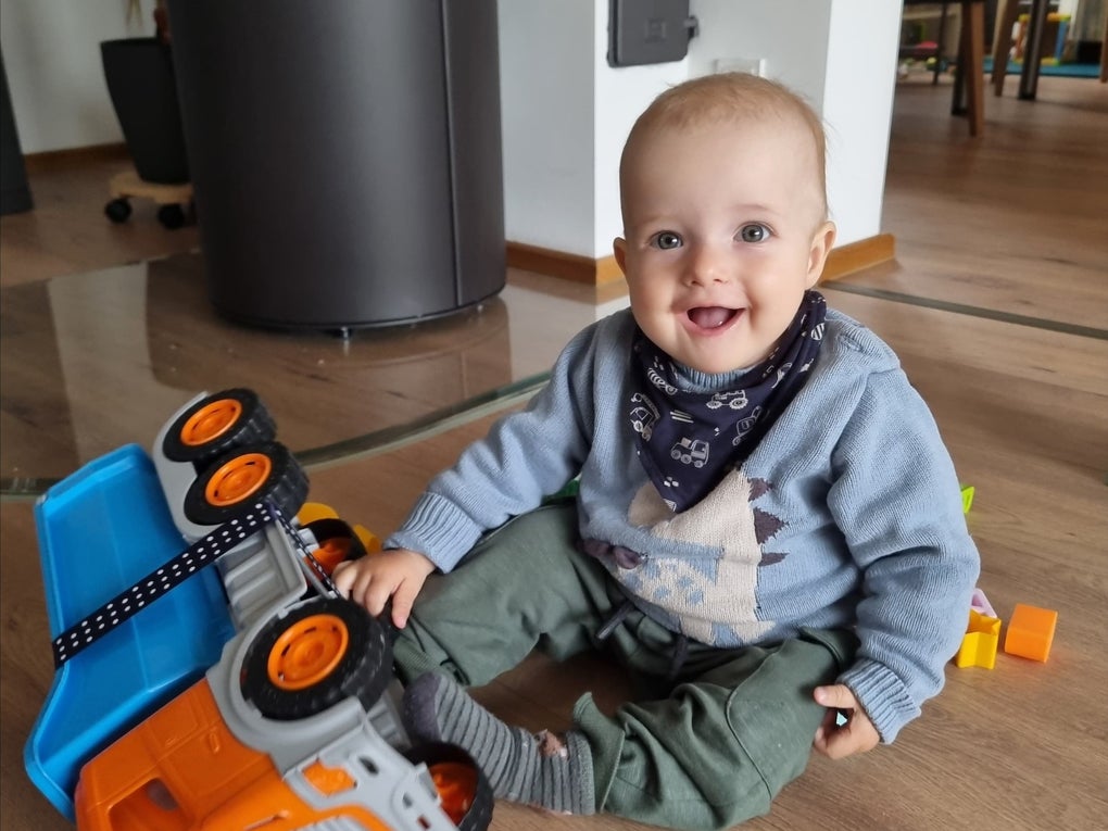 Ein Baby sitzt auf dem Boden und spielt mit einem Spielzeug-LKW Ein Baby sitzt auf dem Boden und spielt mit einem Spielzeug-LKW