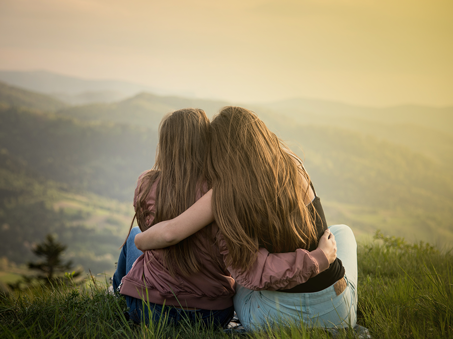 Zwei Frauen sitzen auf einem Hügel mit Blick auf die Berge Zwei Frauen sitzen auf einem Hügel mit Blick auf die Berge