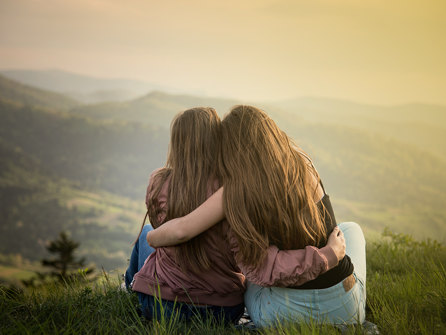Zwei Frauen sitzen auf einem Hügel mit Blick auf die Berge Zwei Frauen sitzen auf einem Hügel mit Blick auf die Berge