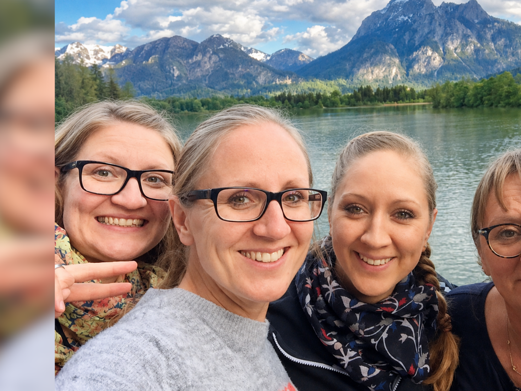 Vier Frauen stehen lächelnd vor einem Gewässer, am Horizont ist ein großer Berg zu sehen. Vier Frauen stehen lächelnd vor einem Gewässer, am Horizont ist ein großer Berg zu sehen.