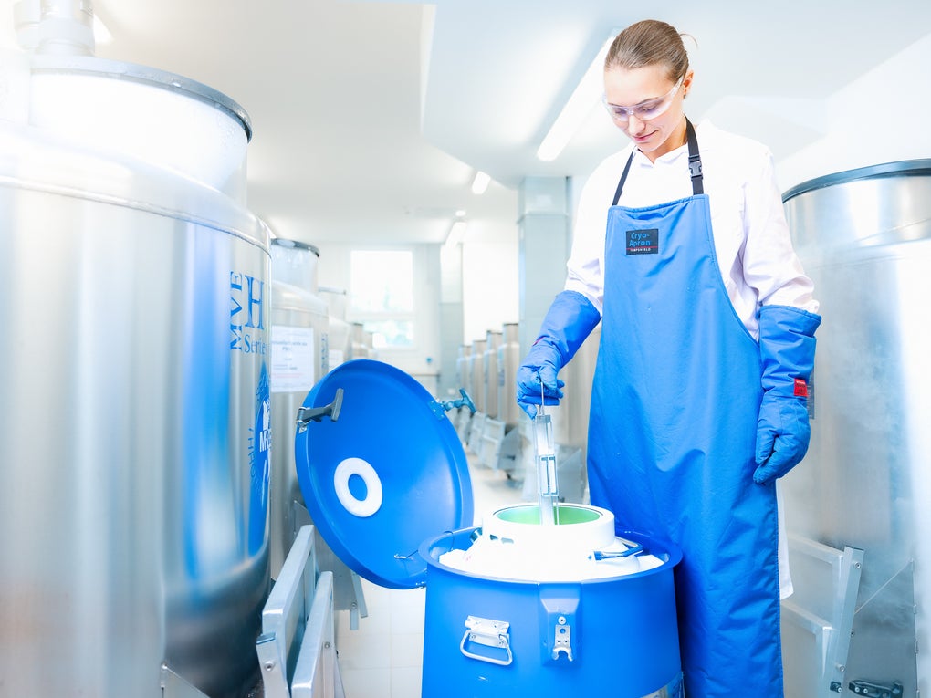 Eine Frau mit einer blauen Schürze und einer Schutzbrille vor einem Kanister Eine Frau mit einer blauen Schürze und einer Schutzbrille vor einem Kanister