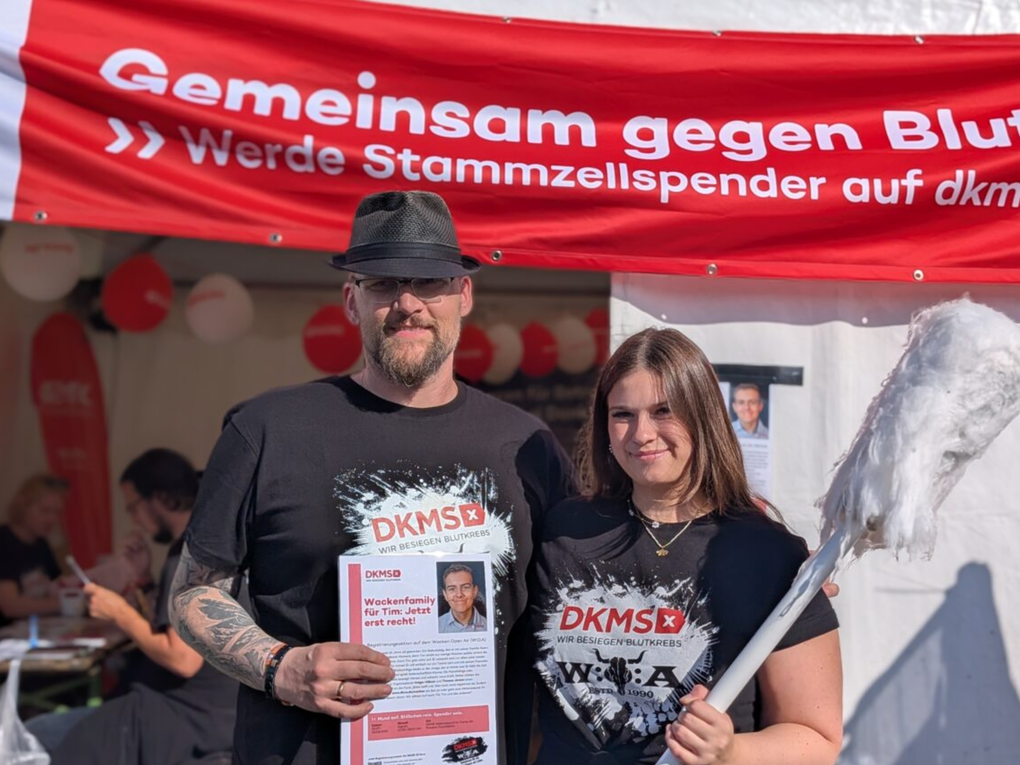 Ein Mann und eine Frau stehen vor einem Schild Ein Mann und eine Frau stehen vor einem Schild