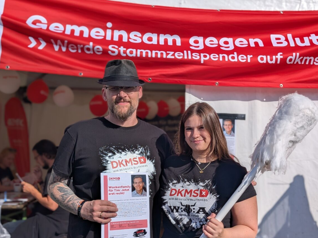 Ein Mann und eine Frau stehen vor einem Schild Ein Mann und eine Frau stehen vor einem Schild