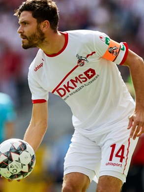 Jonas Hector in FC Köln Trikot, hält einen Ball in der Hand