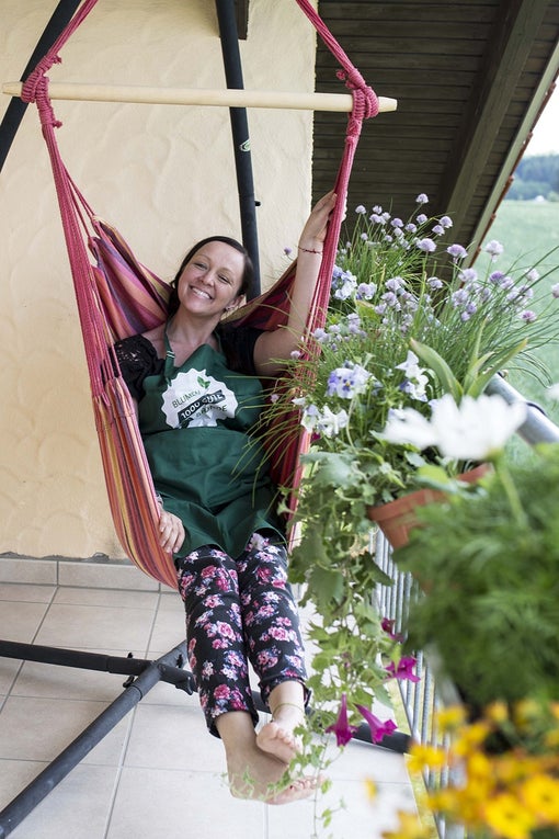 Patientin Stefanie sitzt in einer Hängematte auf dem Balkon und lacht Patientin Stefanie sitzt in einer Hängematte auf dem Balkon und lacht