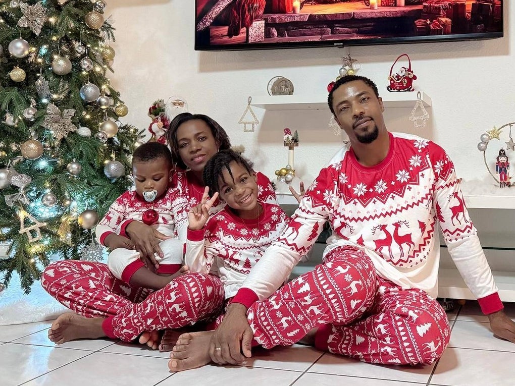 Eine Familie sitzt in passenden Schlafanzügen vor einem geschmückten Tannenbaum. Eine Familie sitzt in passenden Schlafanzügen vor einem geschmückten Tannenbaum.