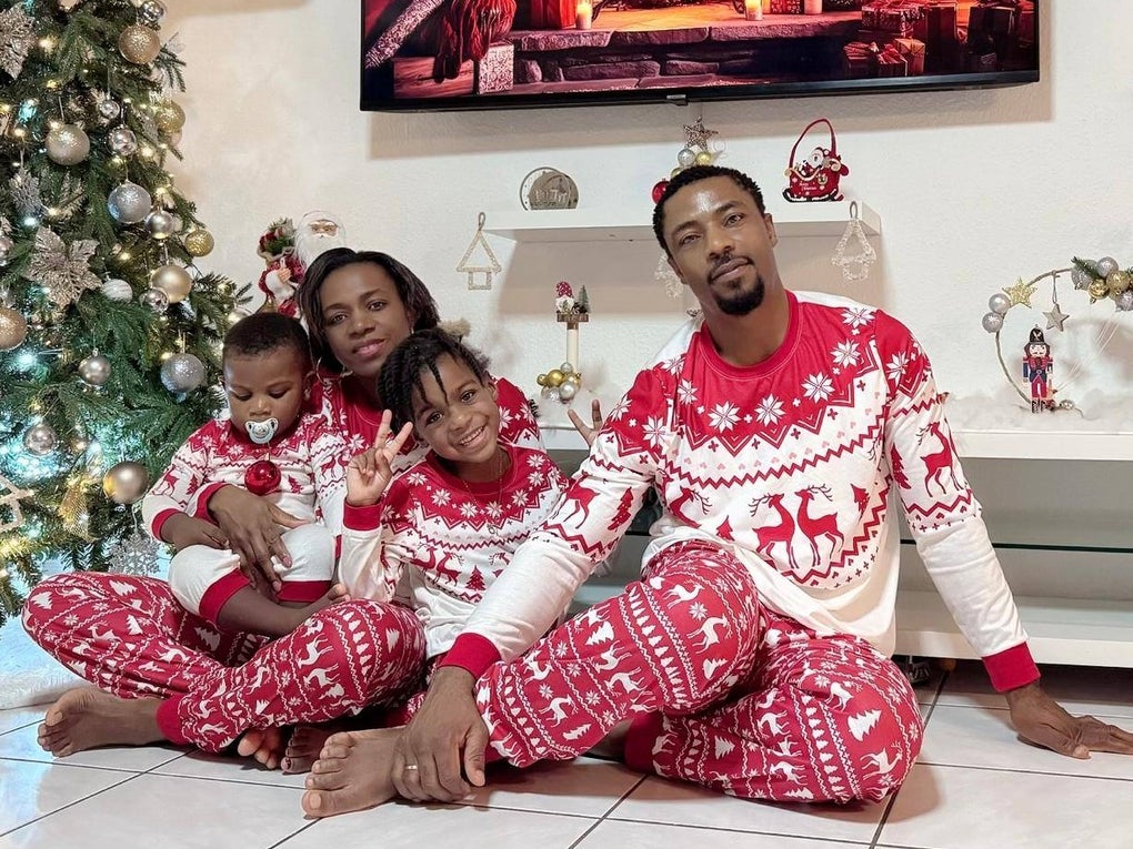 Eine Familie sitzt in passenden Schlafanzügen vor einem geschmückten Tannenbaum. Eine Familie sitzt in passenden Schlafanzügen vor einem geschmückten Tannenbaum.