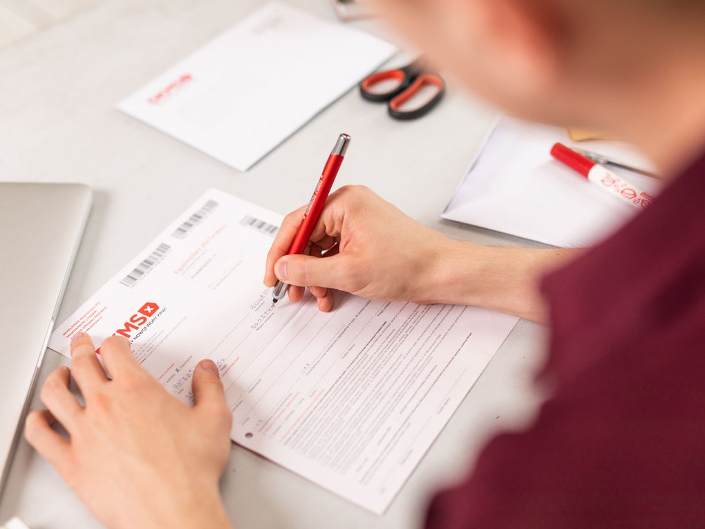 Eine Person, die auf ein Blatt Papier schreibt Eine Person, die auf ein Blatt Papier schreibt