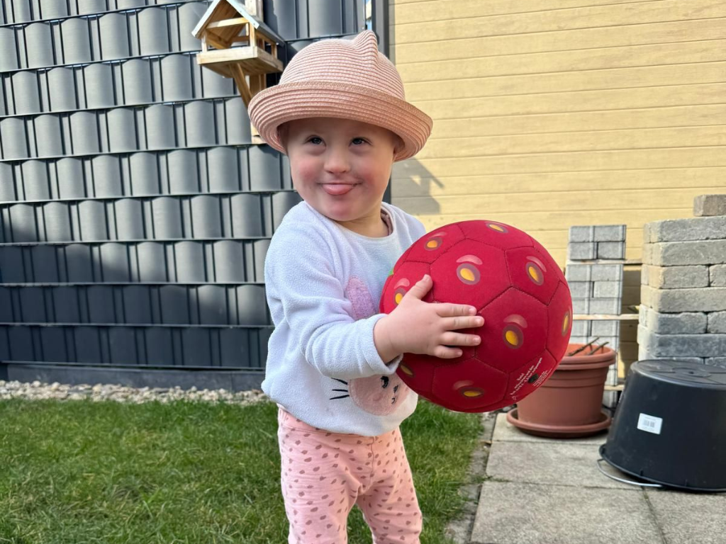 Ein Baby hält einen roten Ball im Garten Ein Baby hält einen roten Ball im Garten