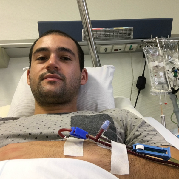 Ein Mann, der in einem Krankenhausbett liegt und an seinem Arm einen Schlauch befestigt hat Ein Mann, der in einem Krankenhausbett liegt und an seinem Arm einen Schlauch befestigt hat