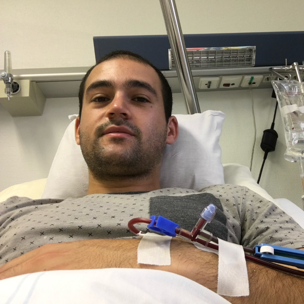 Ein Mann, der in einem Krankenhausbett liegt und an seinem Arm einen Schlauch befestigt hat Ein Mann, der in einem Krankenhausbett liegt und an seinem Arm einen Schlauch befestigt hat