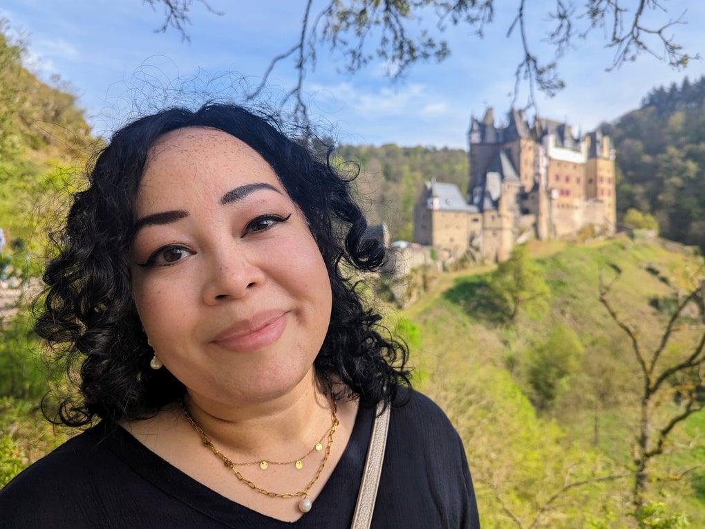 Eine Frau macht ein Selfie mit einer Burg im Hintergrund Eine Frau macht ein Selfie mit einer Burg im Hintergrund