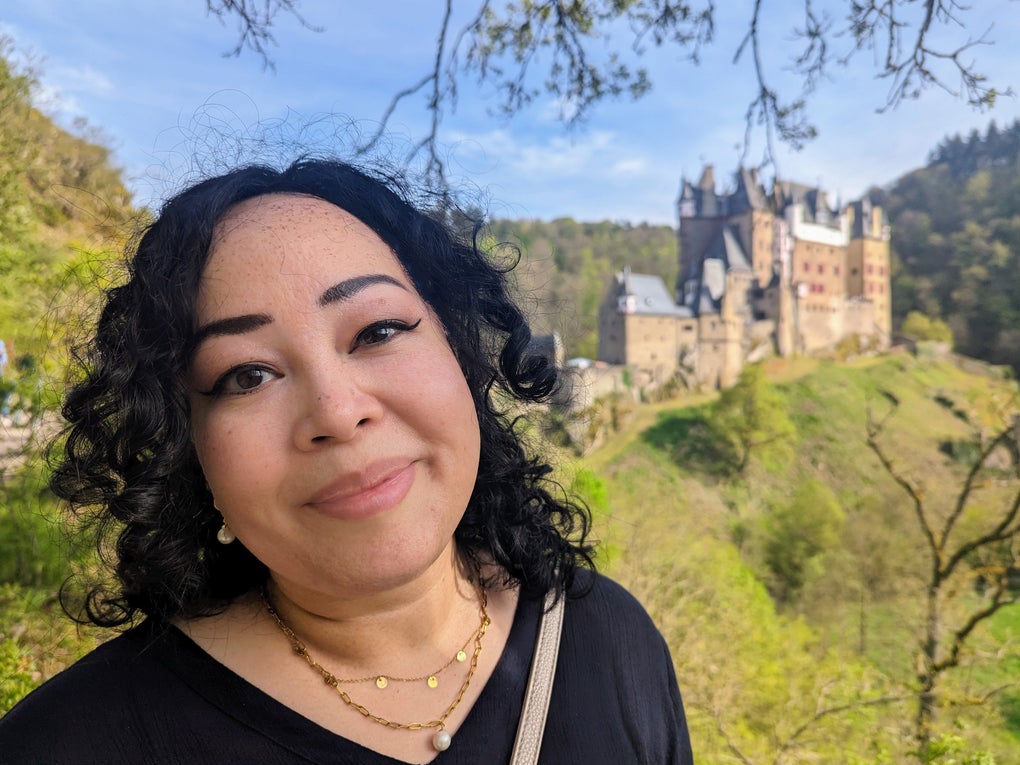 Eine Frau macht ein Selfie mit einer Burg im Hintergrund Eine Frau macht ein Selfie mit einer Burg im Hintergrund