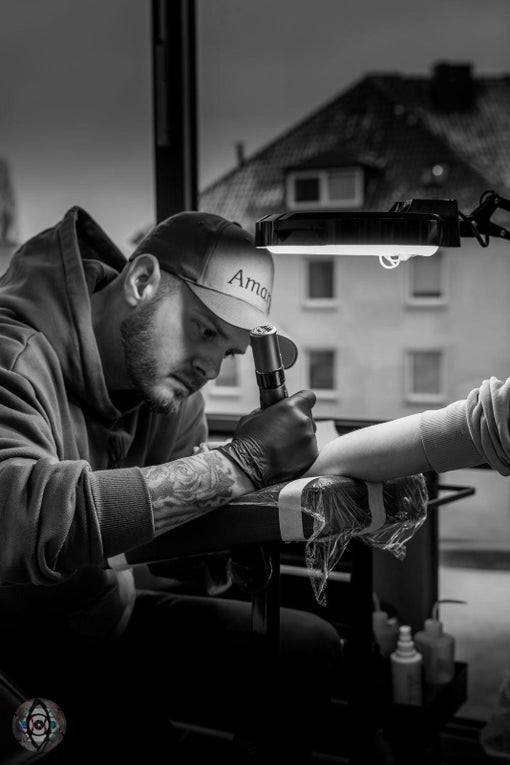 Ein Mann tätowiert einen Arm Ein Mann tätowiert einen Arm