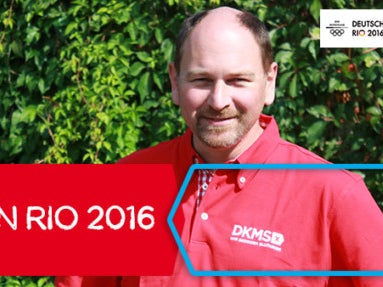 Ein Mann in einem roten Hemd mit DKMS Logo. Auf dem Bild ein rotes Banner mit der Aufschrift DKMS in Rio 2016 Ein Mann in einem roten Hemd mit DKMS Logo. Auf dem Bild ein rotes Banner mit der Aufschrift DKMS in Rio 2016