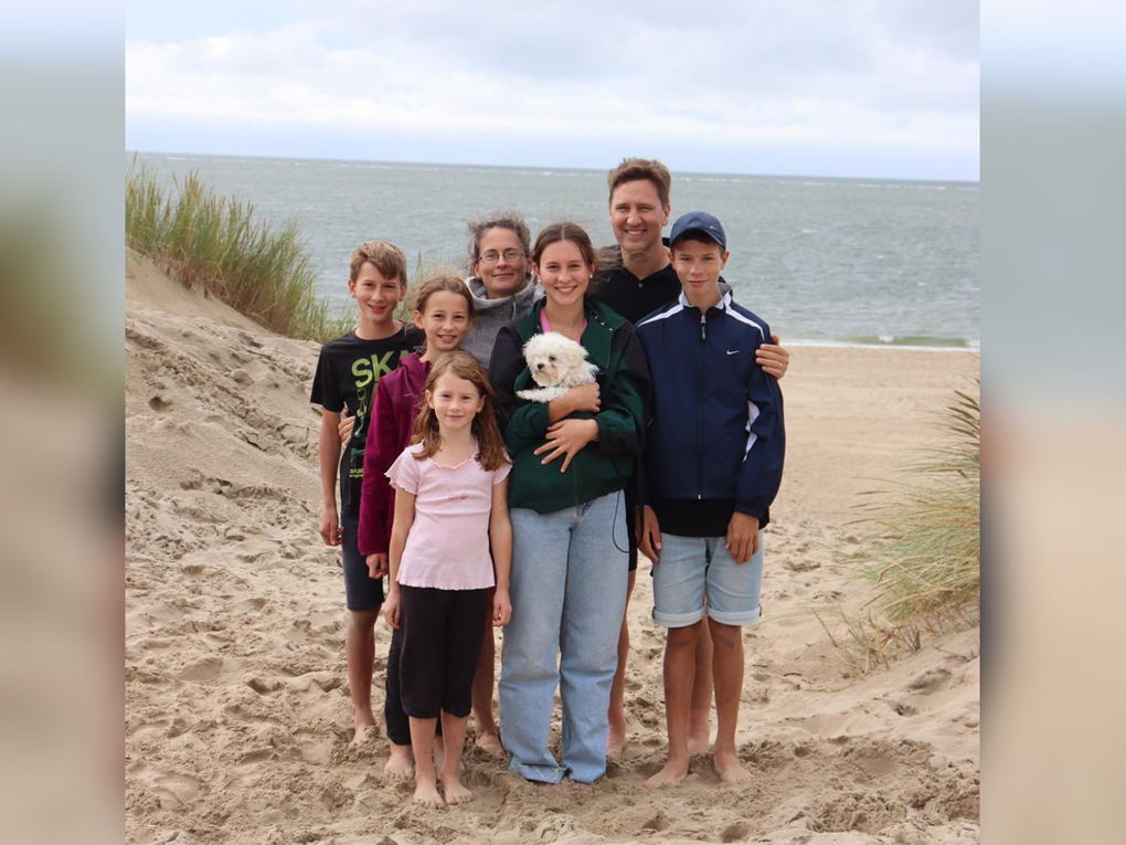 Eine Gruppe von Menschen, die an einem Strand für ein Foto posieren Eine Gruppe von Menschen, die an einem Strand für ein Foto posieren