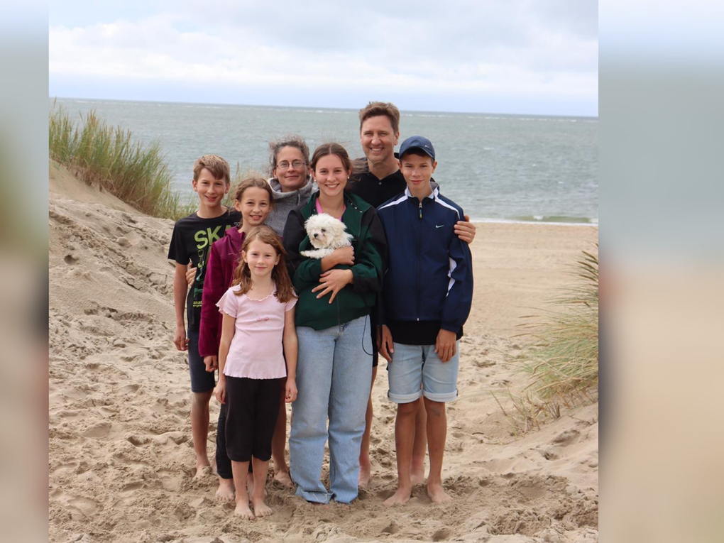 Eine Gruppe von Menschen, die an einem Strand für ein Foto posieren Eine Gruppe von Menschen, die an einem Strand für ein Foto posieren