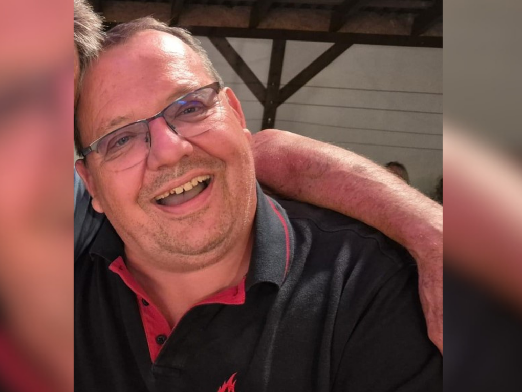 Ein Mann lacht und trägt ein schwarzes Polo-Shirt mit der Aufschrift "Feuerwehr Bruchsal". Ein Mann lacht und trägt ein schwarzes Polo-Shirt mit der Aufschrift "Feuerwehr Bruchsal".