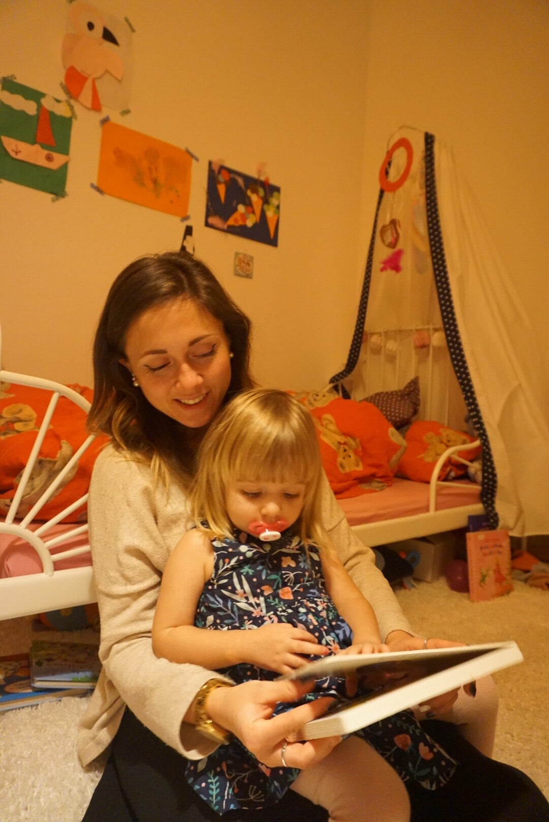 ein kleines Mädchen sitzt auf dem Schoß einer Frau, sie lesen ein Buch zusammen ein kleines Mädchen sitzt auf dem Schoß einer Frau, sie lesen ein Buch zusammen