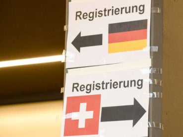 Zwei Schilder mit der Deutschen und Schweizer Flagge, beide mit dem Aufdruck Registrierung und Pfeilen die jeweils in unterschiedliche Richtungen zeigen Zwei Schilder mit der Deutschen und Schweizer Flagge, beide mit dem Aufdruck Registrierung und Pfeilen die jeweils in unterschiedliche Richtungen zeigen