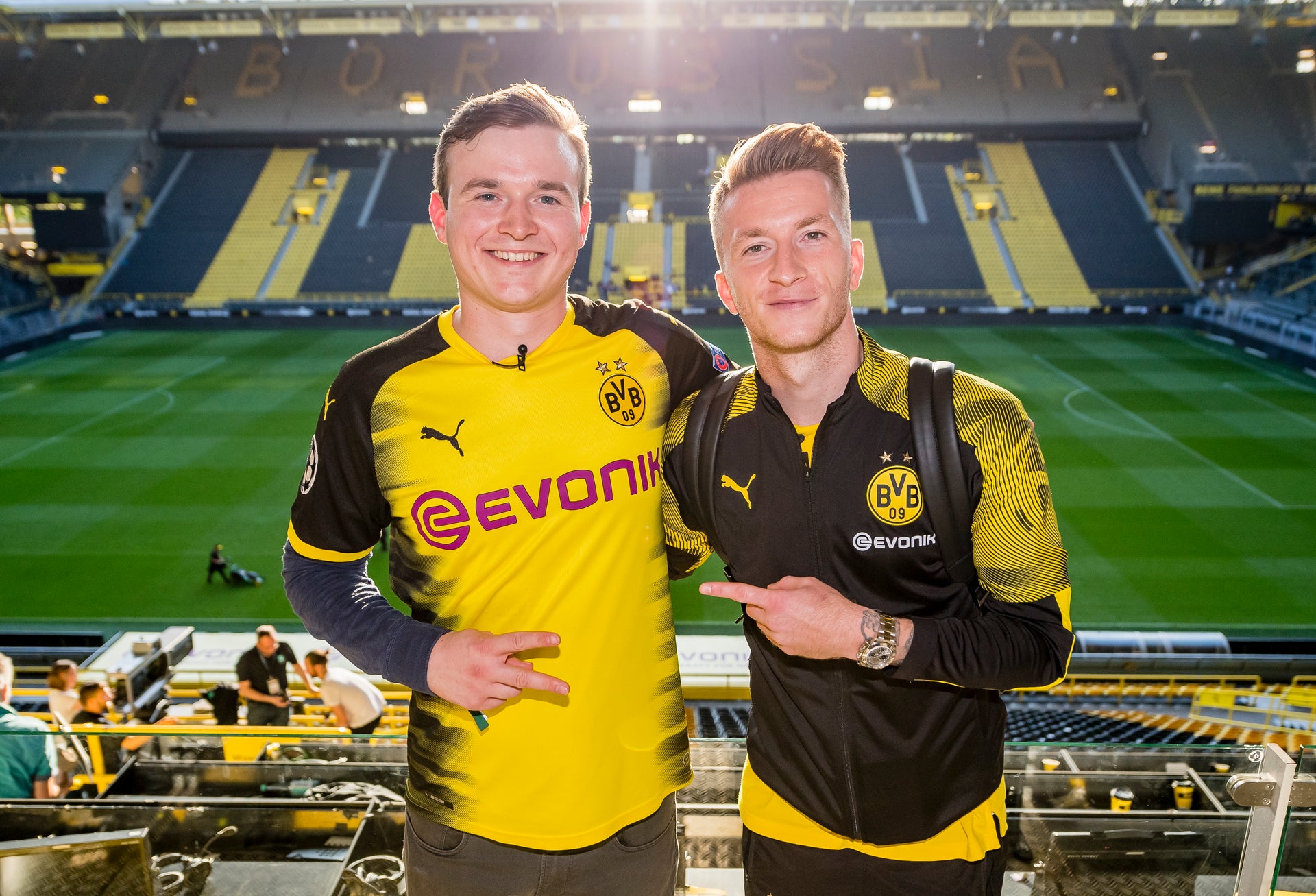 Ludwig Jolmes und Marco Reus im Stadion, beide tragen BVB Merch und im Hintergrund sieht man das BVB Stadion Ludwig Jolmes und Marco Reus im Stadion, beide tragen BVB Merch und im Hintergrund sieht man das BVB Stadion