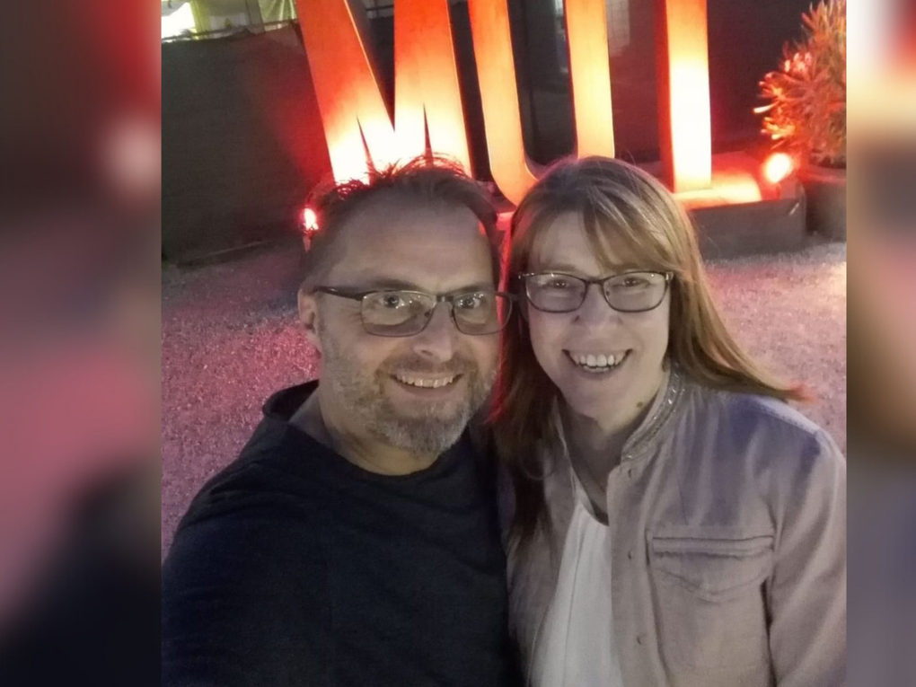 Eine Frau und ein Mann stehen vor einer beleuchteten Schriftskulptur, die "Mut" liest. Eine Frau und ein Mann stehen vor einer beleuchteten Schriftskulptur, die "Mut" liest.