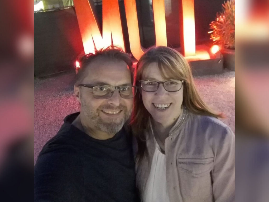 Eine Frau und ein Mann stehen vor einer beleuchteten Schriftskulptur, die "Mut" liest. Eine Frau und ein Mann stehen vor einer beleuchteten Schriftskulptur, die "Mut" liest.