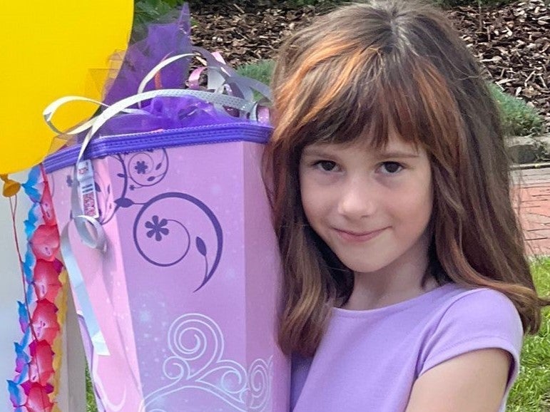 ein Mädchen posiert mit lila Schultüte und lila Kleid für die Kamera ein Mädchen posiert mit lila Schultüte und lila Kleid für die Kamera