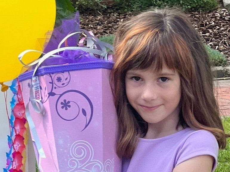 ein Mädchen posiert mit lila Schultüte und lila Kleid für die Kamera ein Mädchen posiert mit lila Schultüte und lila Kleid für die Kamera