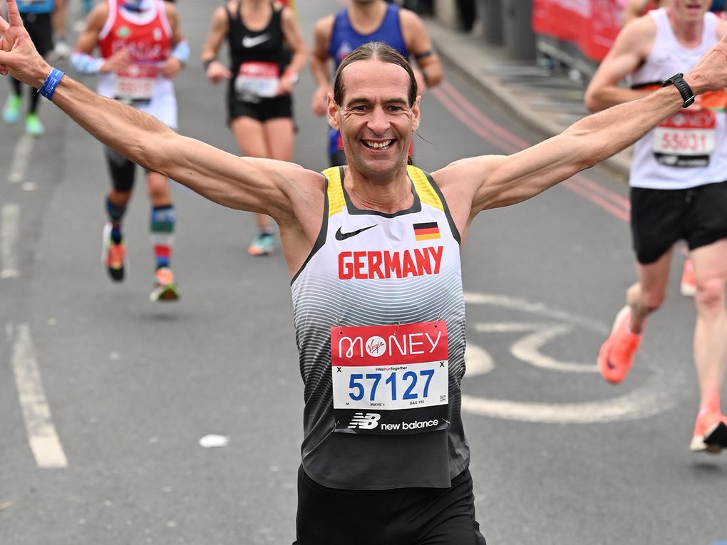 Ein Mann läuft bei einem Straßenmarathon mit ausgestreckten Armen auf die Kamera zu. Er trägt ein Lauftrikot mit der Aufschrift „Germany“, eine Startnummer mit der Ziffer 57127 und ein breites Lächeln im Gesicht. Hinter ihm sind weitere Läuferinnen und Läufer auf der abgesperrten Straße zu sehen.
 Ein Mann läuft bei einem Straßenmarathon mit ausgestreckten Armen auf die Kamera zu. Er trägt ein Lauftrikot mit der Aufschrift „Germany“, eine Startnummer mit der Ziffer 57127 und ein breites Lächeln im Gesicht. Hinter ihm sind weitere Läuferinnen und Läufer auf der abgesperrten Straße zu sehen.