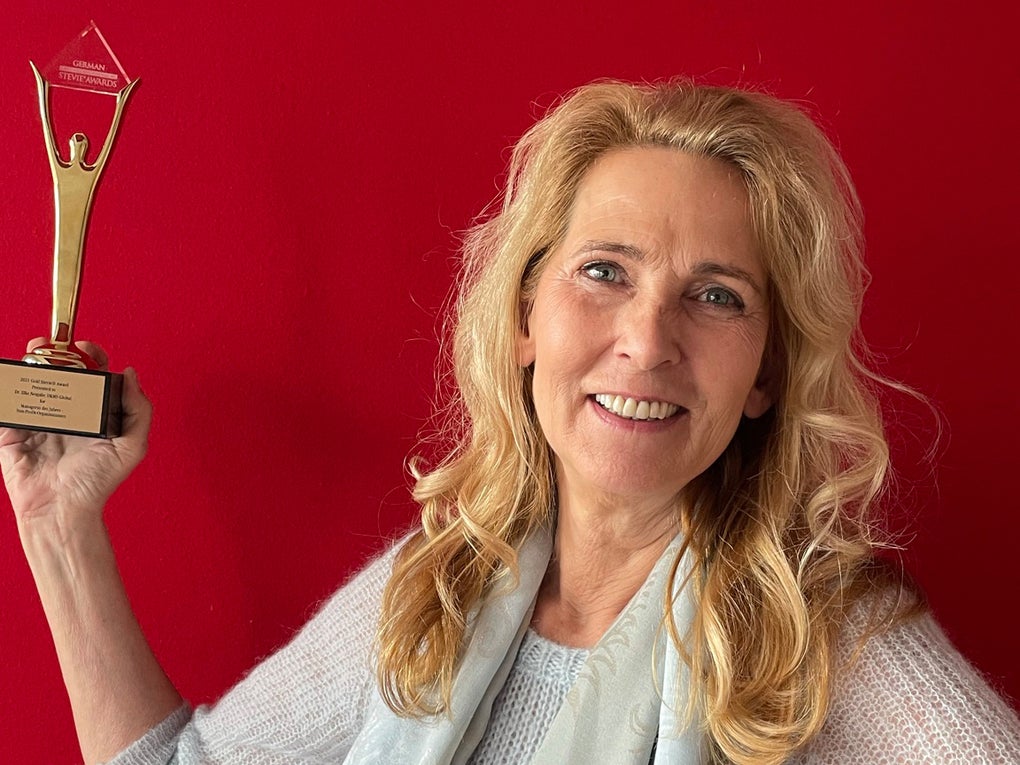 Eine Frau hält einen goldenen Preis hoch und lächelt in die Kamera Eine Frau hält einen goldenen Preis hoch und lächelt in die Kamera