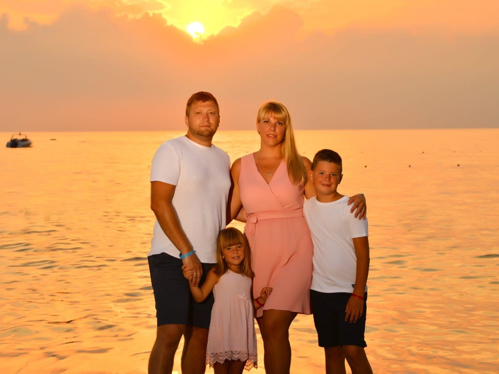 eine Frau und ein Mann stehen mit zwei Kindern vor dem Meer und einem Sonnenuntergang eine Frau und ein Mann stehen mit zwei Kindern vor dem Meer und einem Sonnenuntergang