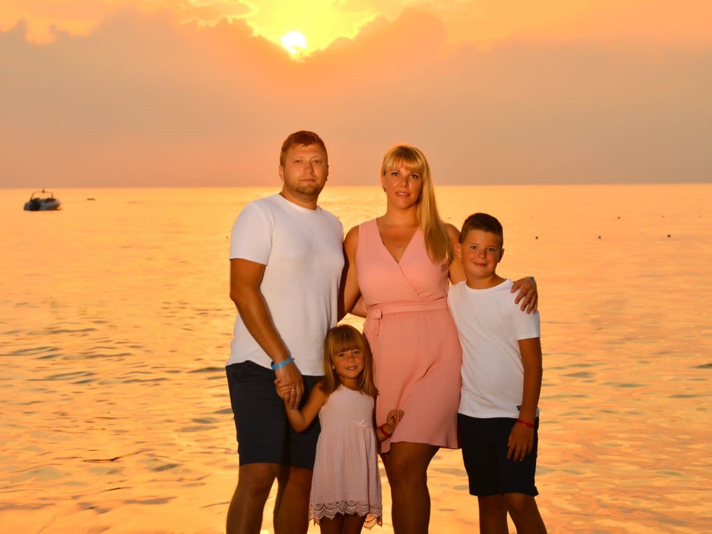 eine Frau und ein Mann stehen mit zwei Kindern vor dem Meer und einem Sonnenuntergang eine Frau und ein Mann stehen mit zwei Kindern vor dem Meer und einem Sonnenuntergang