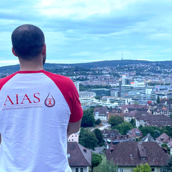 Ein Mann steht auf einem Felsvorsprung und schaut auf eine Stadt Ein Mann steht auf einem Felsvorsprung und schaut auf eine Stadt