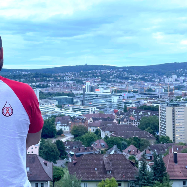 Ein Mann steht auf einem Felsvorsprung und schaut auf eine Stadt Ein Mann steht auf einem Felsvorsprung und schaut auf eine Stadt