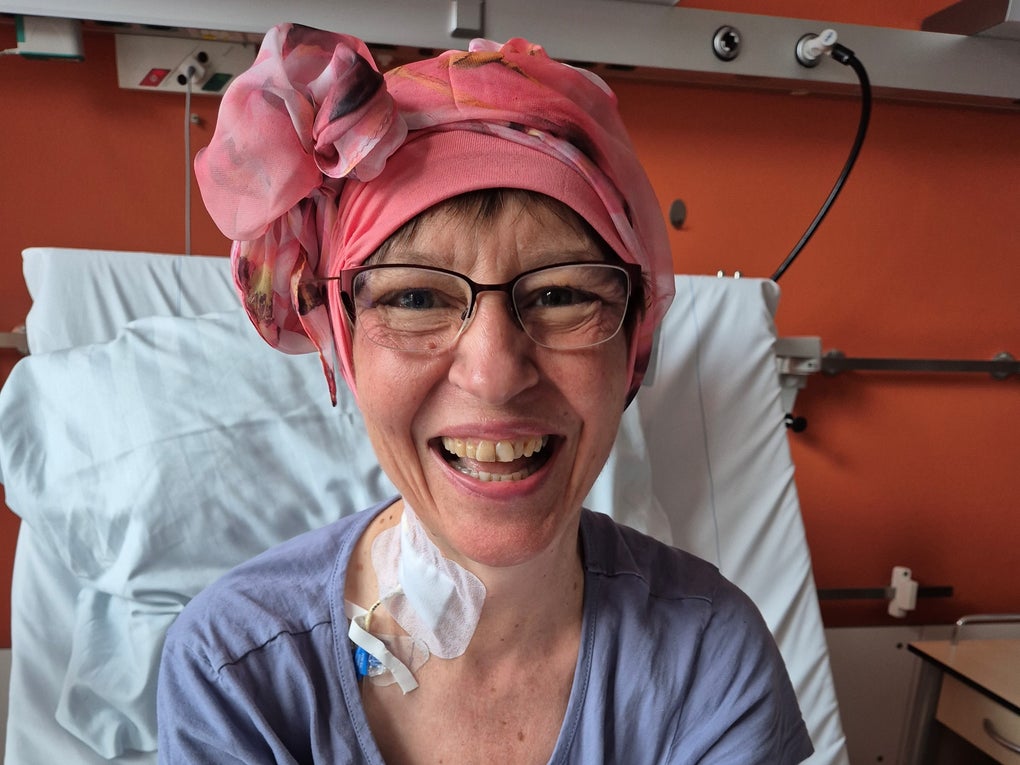 Eine Frau mit rosa Kopfbedeckung lächelt Eine Frau mit rosa Kopfbedeckung lächelt