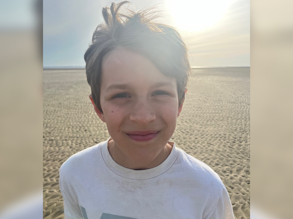 Ein Junge steht am Strand und lacht in die Kamera. Ein Junge steht am Strand und lacht in die Kamera.