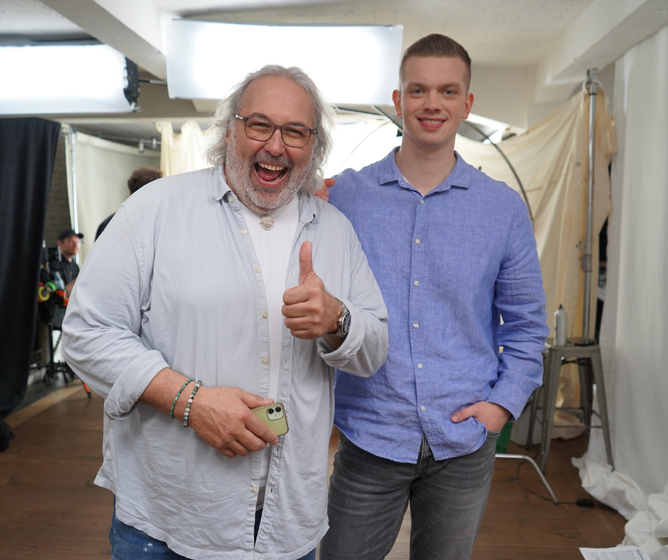 Ein Mann und ein Mann posieren auf einem Videoset für ein Foto, einer davon streckt den Daumen nach oben. Ein Mann und ein Mann posieren auf einem Videoset für ein Foto, einer davon streckt den Daumen nach oben.